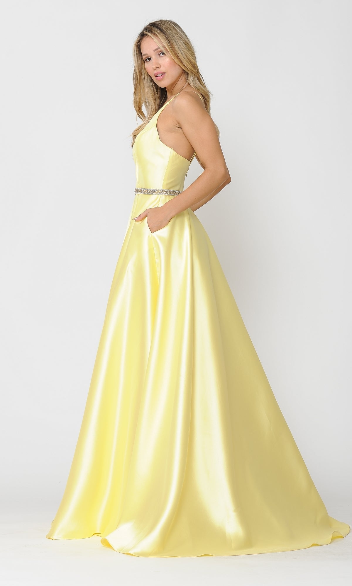 A woman models the Long A-Line Mikado Prom Gown 8690 with pockets—a sleeveless, floor-length yellow dress with a fitted bodice and side cutouts—against a plain white background.